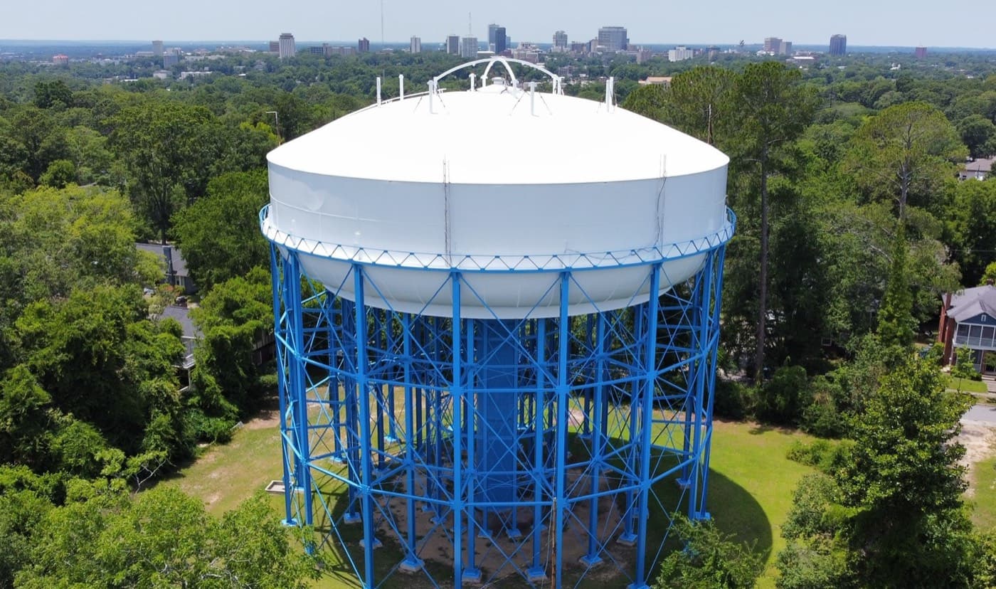 Aerial view of the Columbia Melrose Heights water tank, a white bowl on blue steel legs, with the downtown Columbia, SC skyline behind it