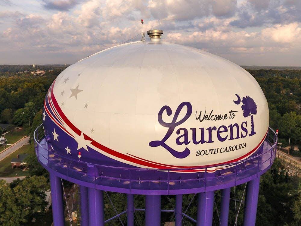 Laurens Fleming St water tank with a purple, red and white 'Welcome to Laurens, South Carolina' mural and palmetto