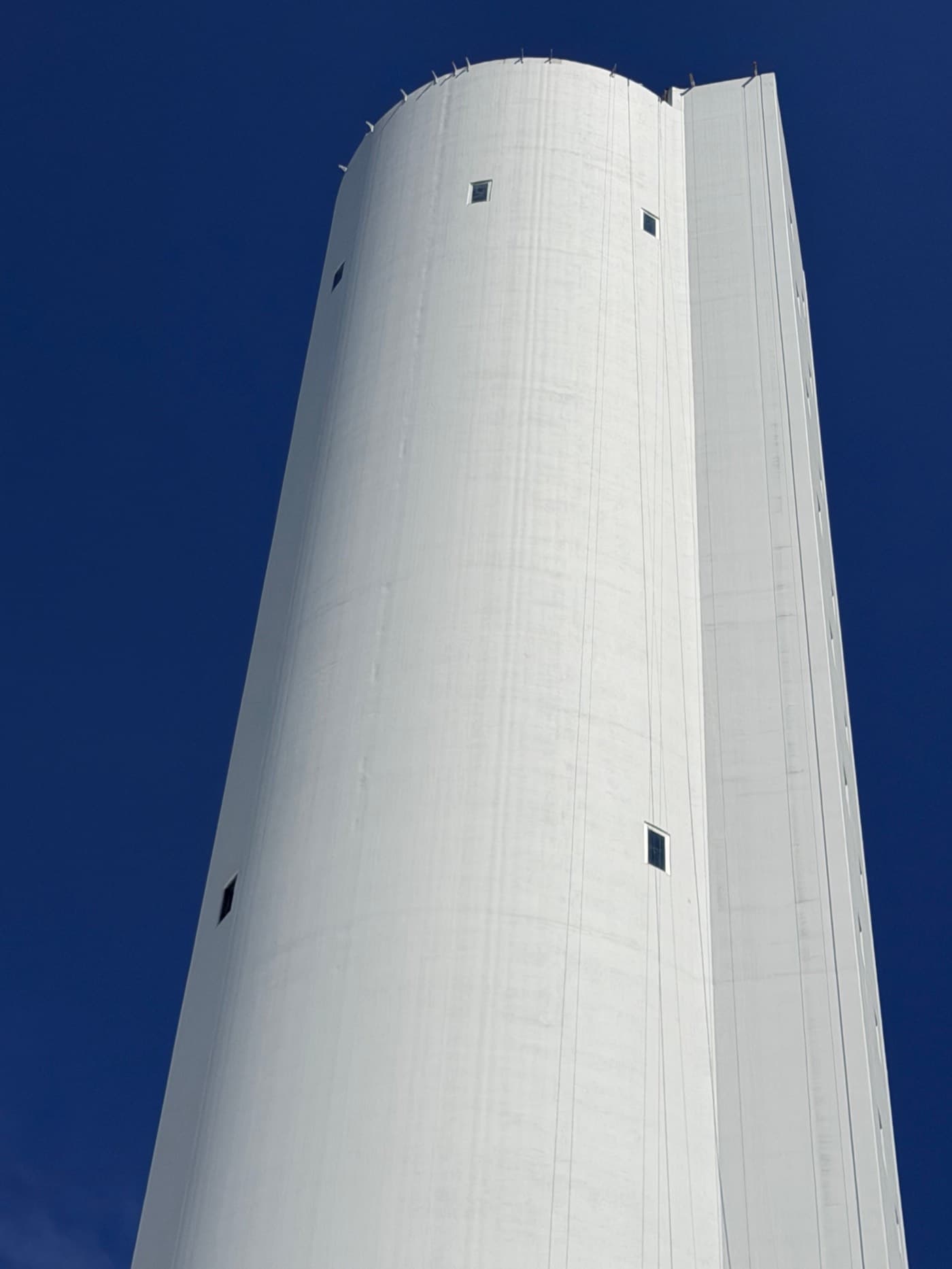 Freshly coated white Prysmian tower against a deep blue sky